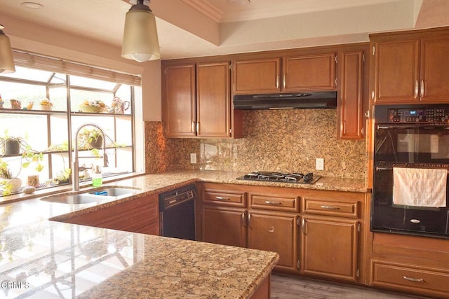 kitchen featuring under cabinet range hood, black appliances, brown cabinetry, and a sink