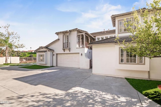 view of front of home with fence, a tiled roof, stucco siding, a garage, and driveway