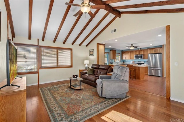 living area with visible vents, ceiling fan, beamed ceiling, high vaulted ceiling, and wood-type flooring