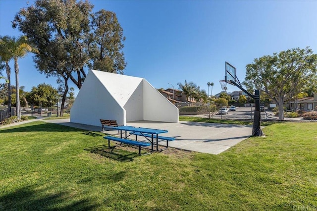 surrounding community with a lawn, community basketball court, and fence