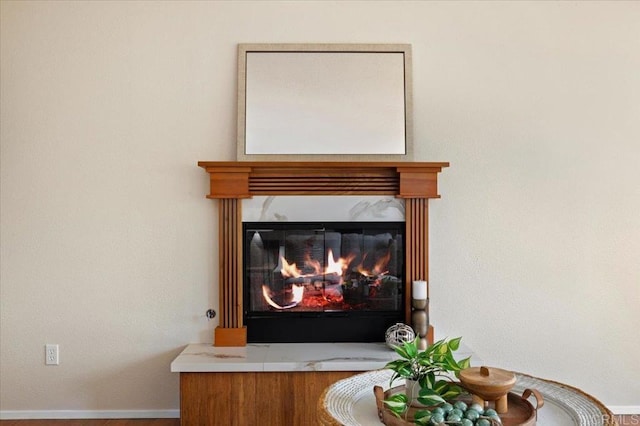 details featuring baseboards and a glass covered fireplace