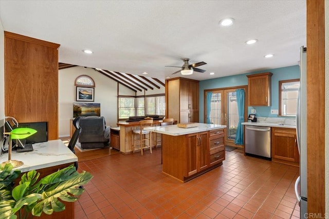 kitchen featuring stainless steel dishwasher, brown cabinetry, and light countertops