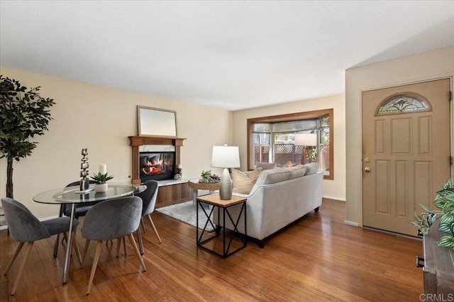 living room with a glass covered fireplace, wood finished floors, and baseboards