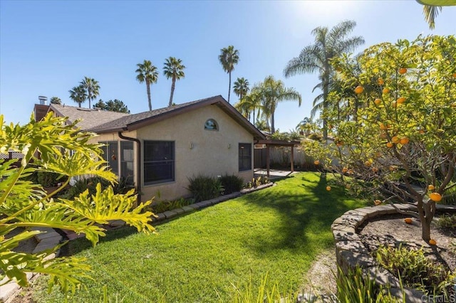 exterior space featuring a yard, fence, and stucco siding