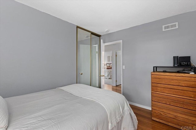 bedroom featuring visible vents, baseboards, and wood finished floors