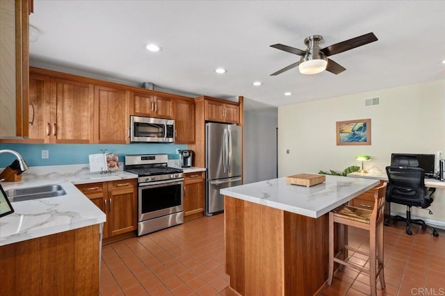 kitchen with tile patterned floors, brown cabinets, appliances with stainless steel finishes, and a sink