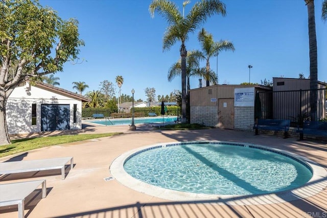 pool with a patio, an outdoor structure, and fence