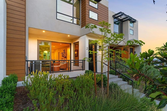 exterior entry at dusk featuring stucco siding