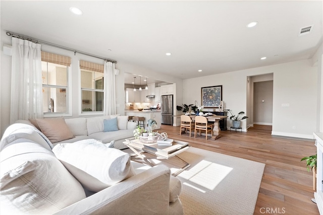 living area featuring light wood-style flooring, recessed lighting, visible vents, and baseboards