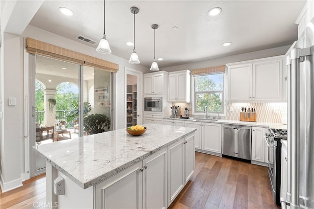 kitchen with visible vents, a sink, a center island, appliances with stainless steel finishes, and white cabinets