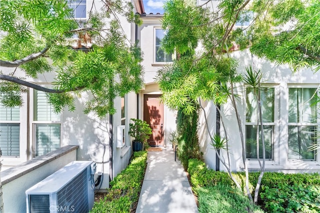 doorway to property featuring stucco siding and ac unit