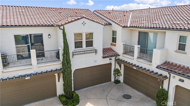 mediterranean / spanish home featuring stucco siding, concrete driveway, an attached garage, and a tile roof