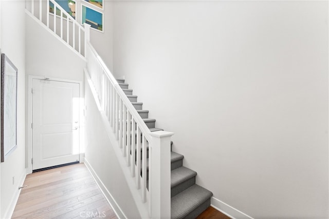 stairs with a high ceiling, baseboards, and hardwood / wood-style floors