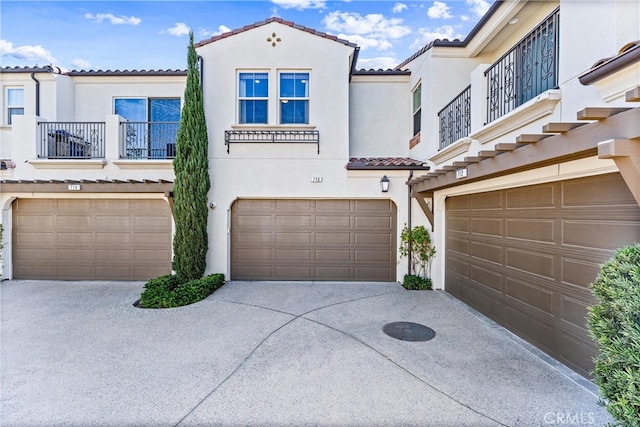 view of front of home featuring stucco siding, driveway, an attached garage, and a tile roof