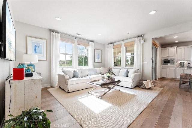 living area with visible vents, recessed lighting, light wood-type flooring, and baseboards