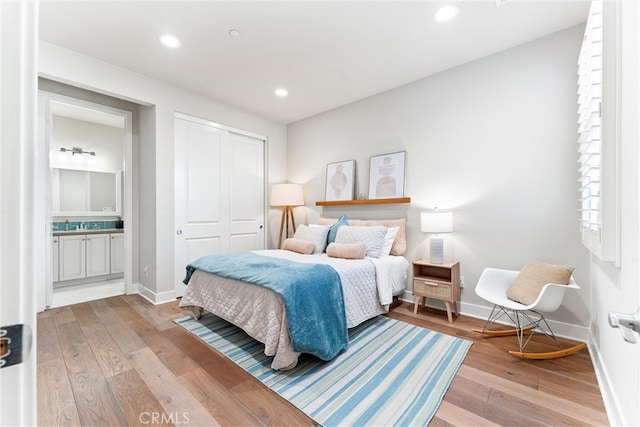 bedroom with light wood finished floors, baseboards, recessed lighting, a closet, and ensuite bath