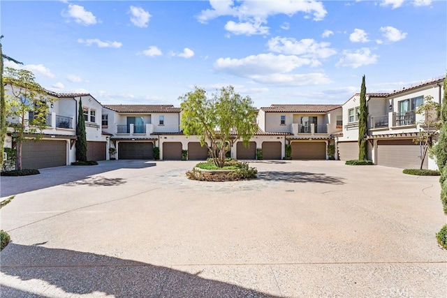 view of front of home featuring a tile roof, a garage, a residential view, and stucco siding