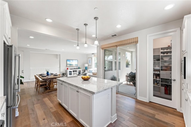 kitchen with visible vents, white cabinetry, freestanding refrigerator, and wood-type flooring