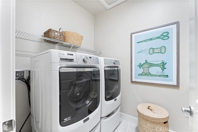 clothes washing area with washer and dryer, baseboards, and laundry area