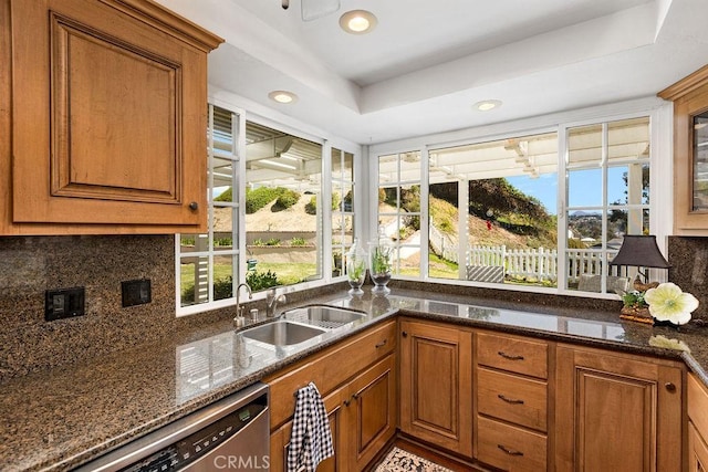 kitchen with backsplash, brown cabinets, stainless steel dishwasher, and a sink