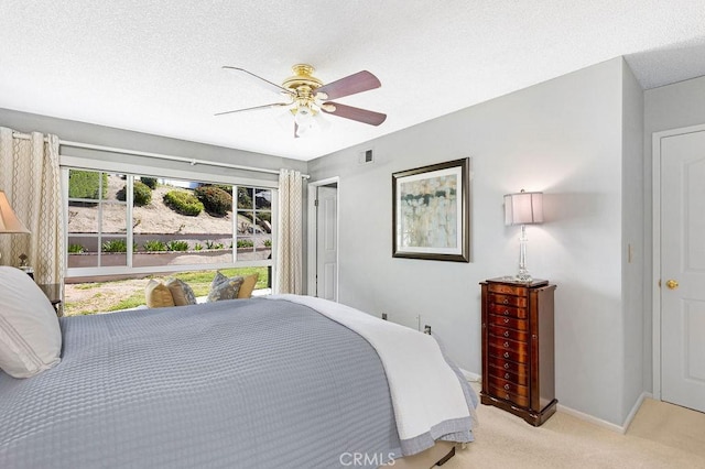 bedroom featuring baseboards, visible vents, ceiling fan, a textured ceiling, and light carpet