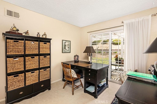 office space with a textured ceiling, baseboards, visible vents, and light carpet