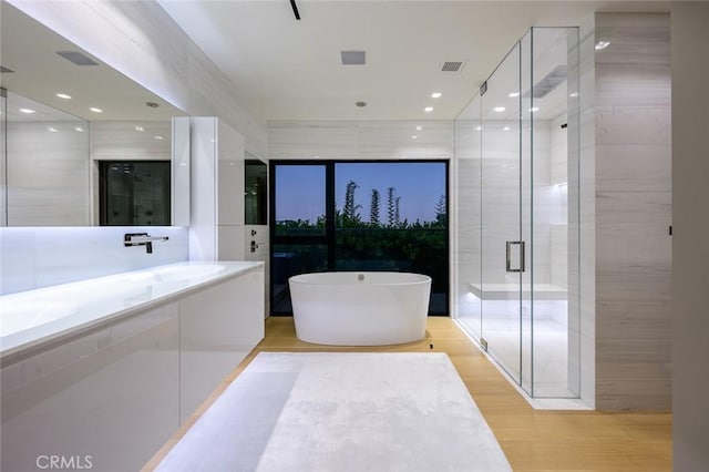 bathroom with vanity, wood finished floors, visible vents, a stall shower, and a freestanding bath