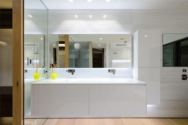 bathroom with double vanity, wood finished floors, and a sink