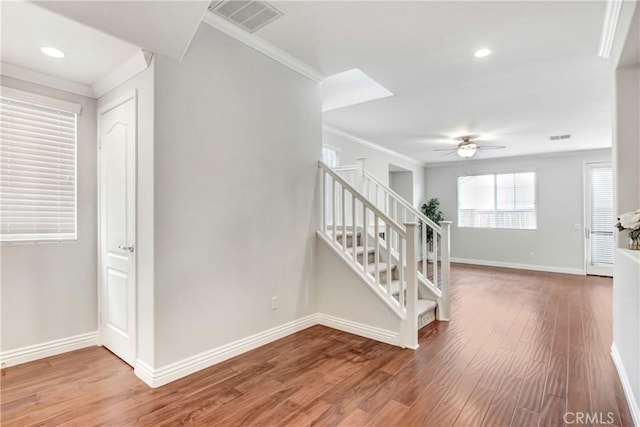 stairway featuring visible vents, wood finished floors, baseboards, and ornamental molding