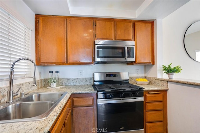 kitchen with a sink, stainless steel appliances, and brown cabinetry