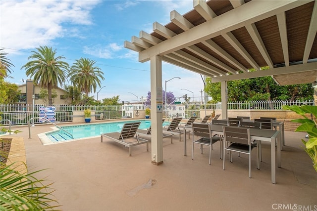 community pool with a patio area and fence