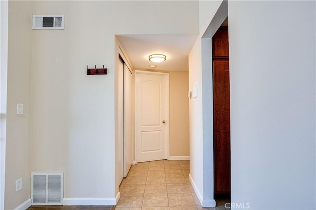 hallway with light tile patterned flooring, visible vents, and baseboards