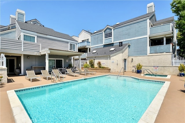 back of property featuring a community pool, a balcony, a community hot tub, and a patio area