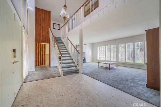 unfurnished living room featuring tile patterned floors, stairway, carpet, and a high ceiling