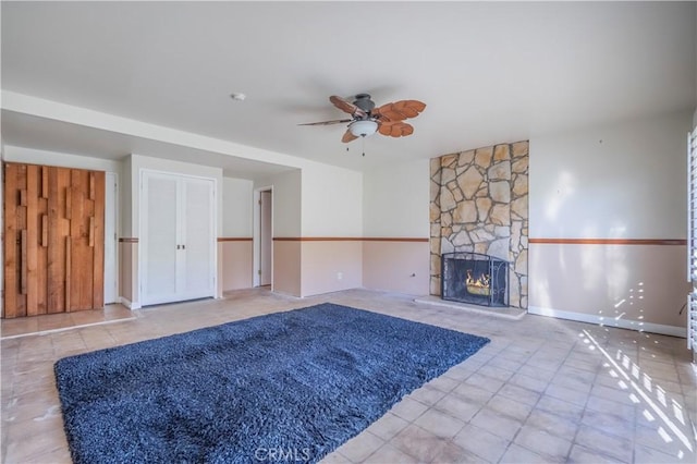 unfurnished living room with a fireplace, a ceiling fan, and baseboards