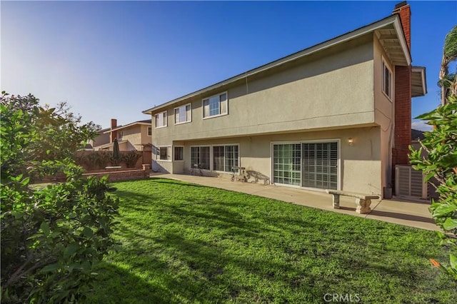 back of property featuring fence, stucco siding, central air condition unit, a patio area, and a lawn