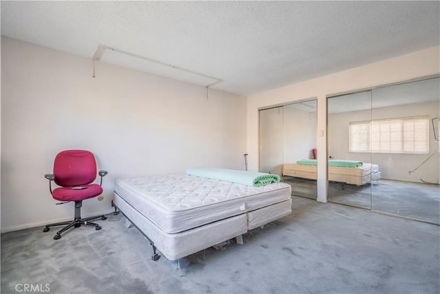 bedroom featuring a textured ceiling, two closets, and carpet floors