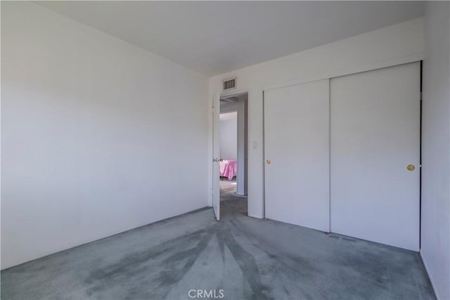 unfurnished bedroom with visible vents, carpet, and a closet