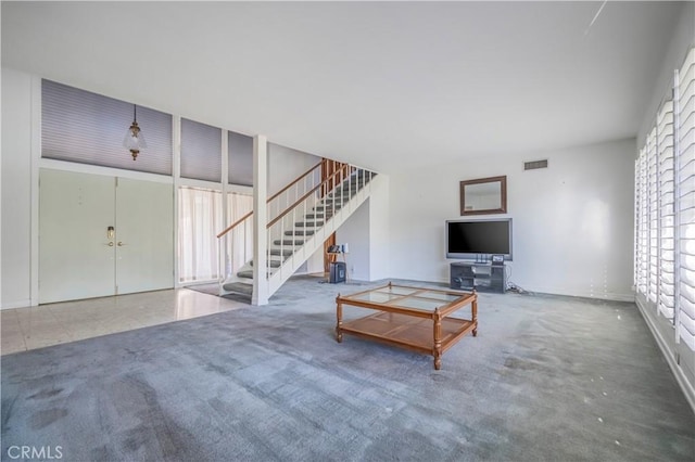 unfurnished living room featuring visible vents, stairs, baseboards, and carpet floors