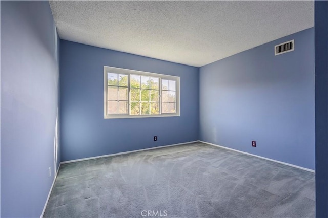 carpeted spare room featuring baseboards, visible vents, and a textured ceiling