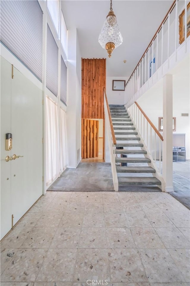 stairway featuring a wealth of natural light, visible vents, and a towering ceiling