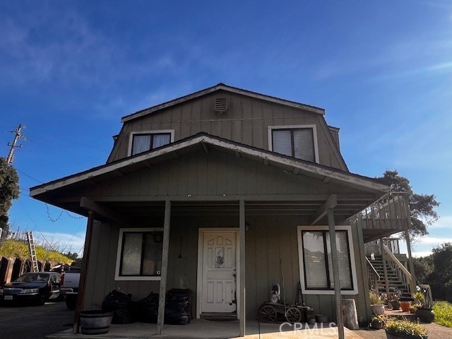 view of front facade with board and batten siding and stairs