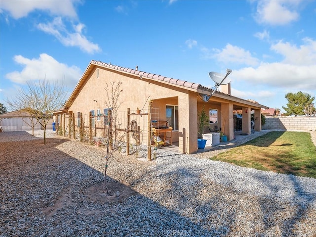 rear view of property with fence, stucco siding, a chimney, a yard, and a patio