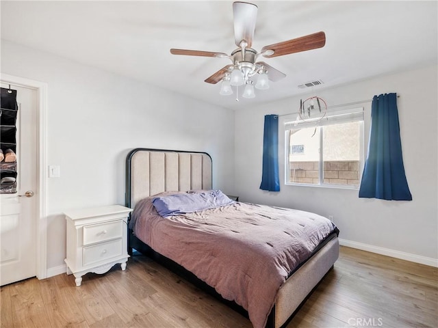 bedroom featuring ceiling fan, visible vents, baseboards, and light wood-style flooring