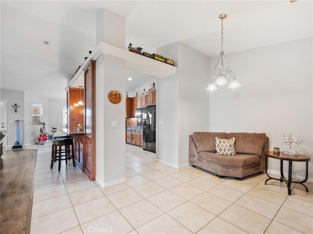 living room with light tile patterned floors, a notable chandelier, and baseboards