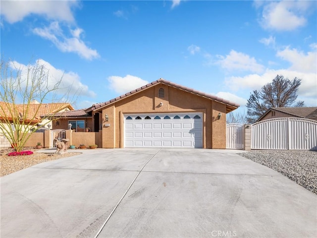 view of front facade featuring stucco siding, a gate, fence, concrete driveway, and an attached garage