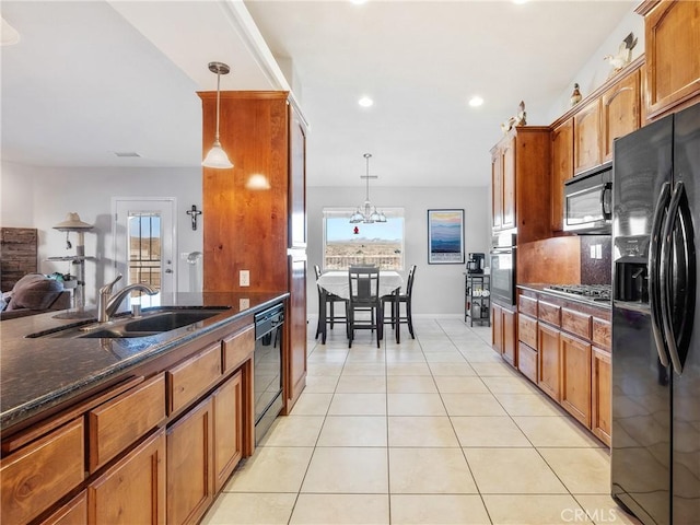 kitchen featuring brown cabinets, black appliances, a sink, plenty of natural light, and light tile patterned flooring