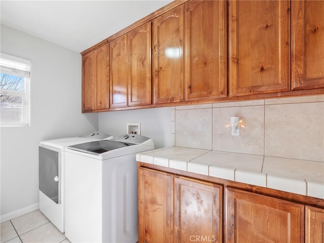 laundry room with washer and clothes dryer, cabinet space, baseboards, and light tile patterned flooring