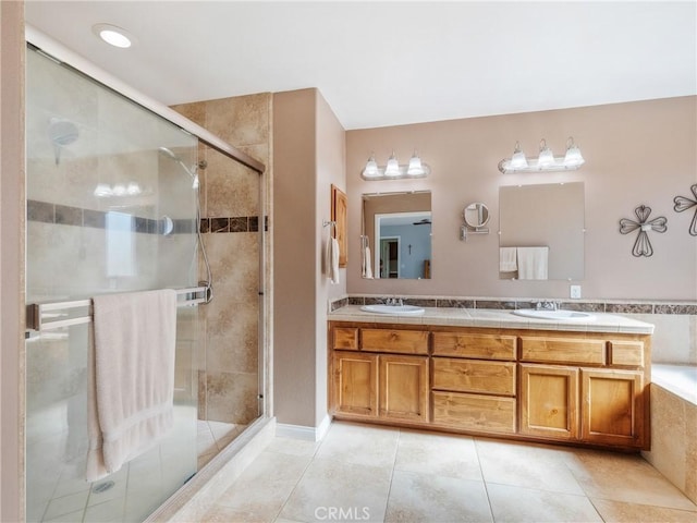 bathroom with double vanity, a shower stall, and a sink