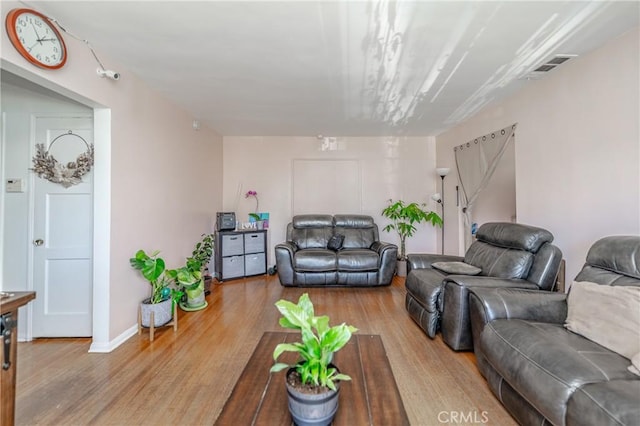 living area with wood finished floors, visible vents, and baseboards